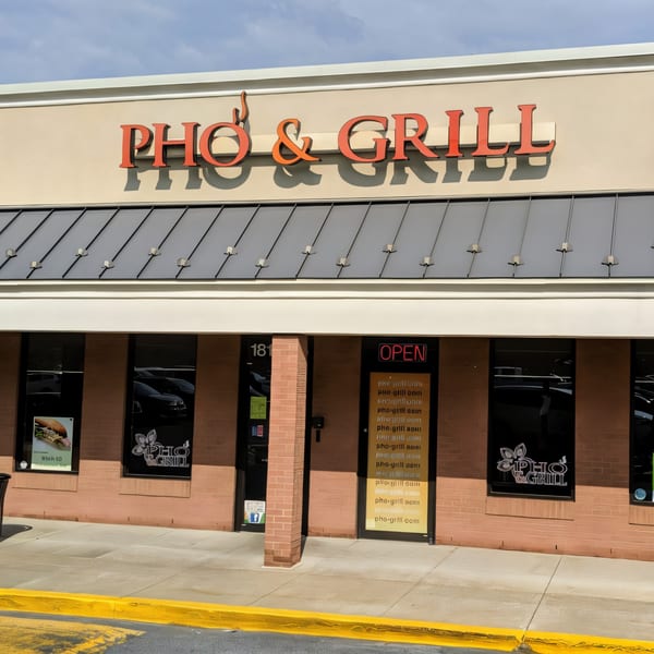 Exterior of Pho & Grill restaurant with its orange sign and an "OPEN" sign in the window.