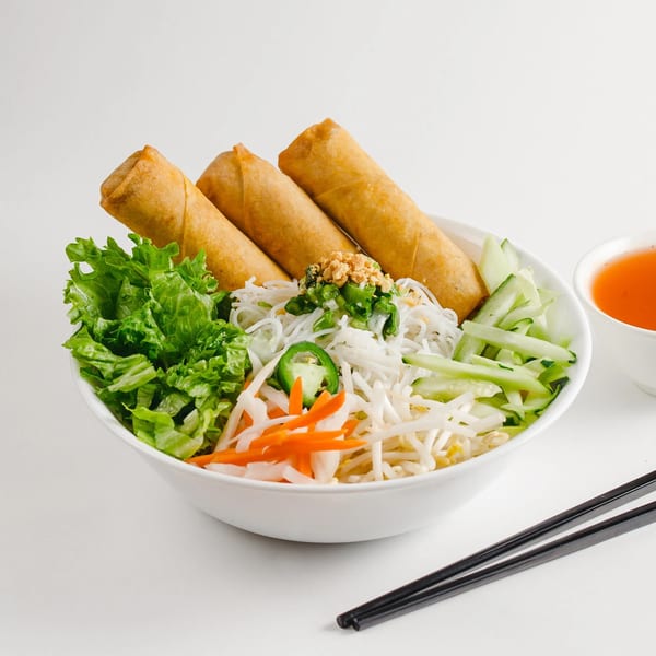Vietnamese vermicelli bowl with crispy spring rolls, fresh lettuce, bean sprouts, carrots, and cucumbers.