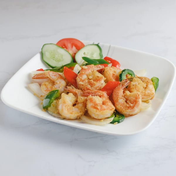 Salt and pepper shrimp with bell peppers, onions, and a side of sliced cucumbers and tomatoes.