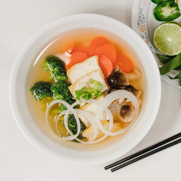 Vegetable pho with tofu, broccoli, carrots, and onions, served with lime and jalapeños.