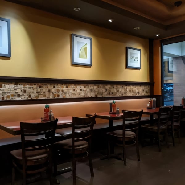 Interior of Pho & Grill with booths, tables, chairs, and framed art on mustard yellow walls.